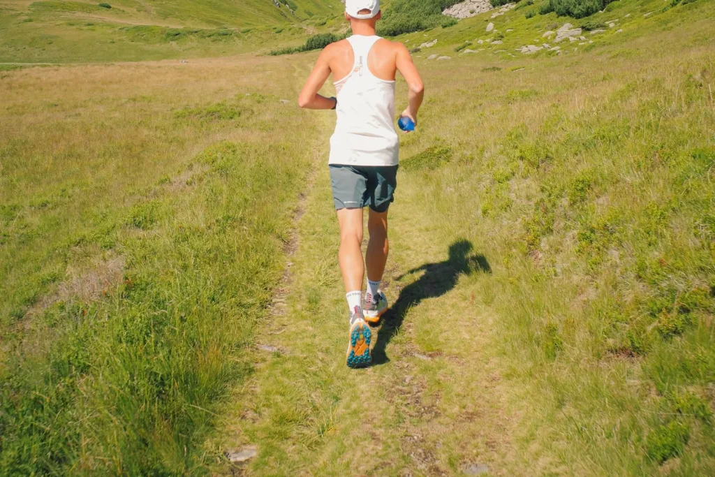 Previsioni running: runner di spalle su un sentiero erboso di montagna