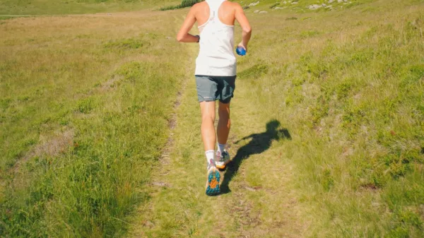 Previsioni running: runner di spalle su un sentiero erboso di montagna