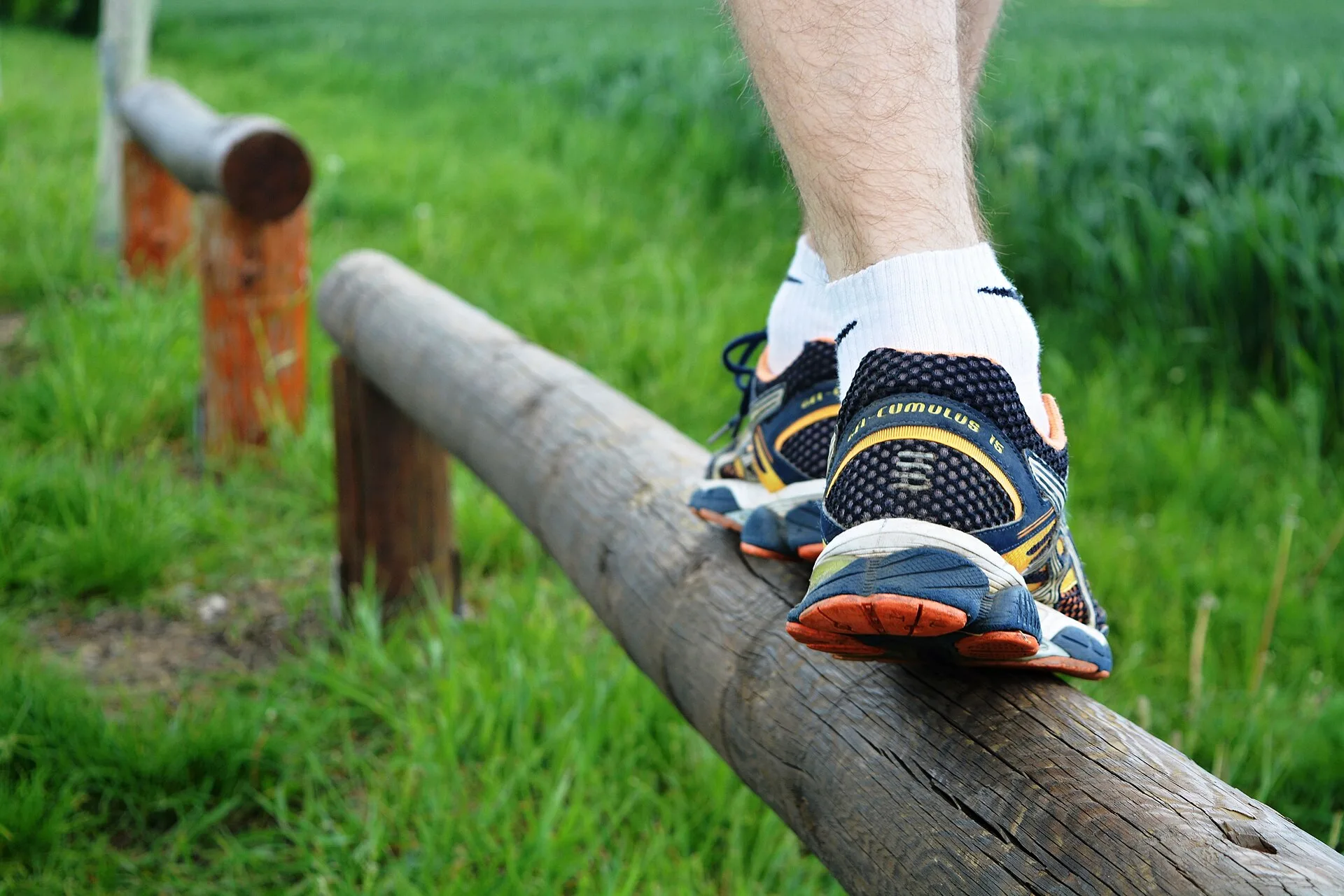 Piede di un runner con scarpa da corsa appoggiato su un tronco in un prato