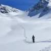 Scialpinista in salita lungo una traccia in un ampio vallone innevato
